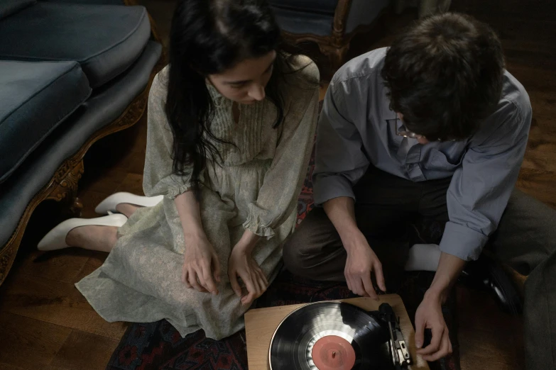 a man and a woman sitting on the floor next to a record player, inspired by Wilhelm Hammershøi, pexels contest winner, renaissance, film still from horror movie, high angle close up shot, cinematic outfit photo, lorde