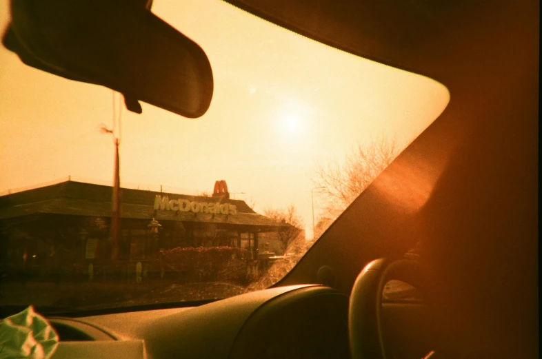 a view of the sun through the windshield of a car, an album cover, inspired by Elsa Bleda, photorealism, golden arches, suns, mc donalds, 35mm —w 1920 —h 1080