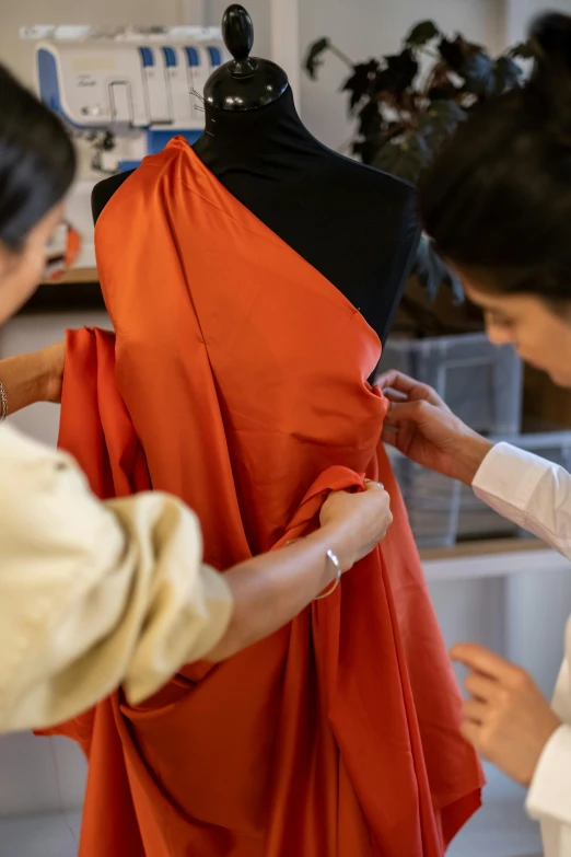 two women looking at a dress on a mannequin, pexels contest winner, renaissance, wearing an orange jumpsuit, work in progress, pictured from the shoulders up, wearing hakama