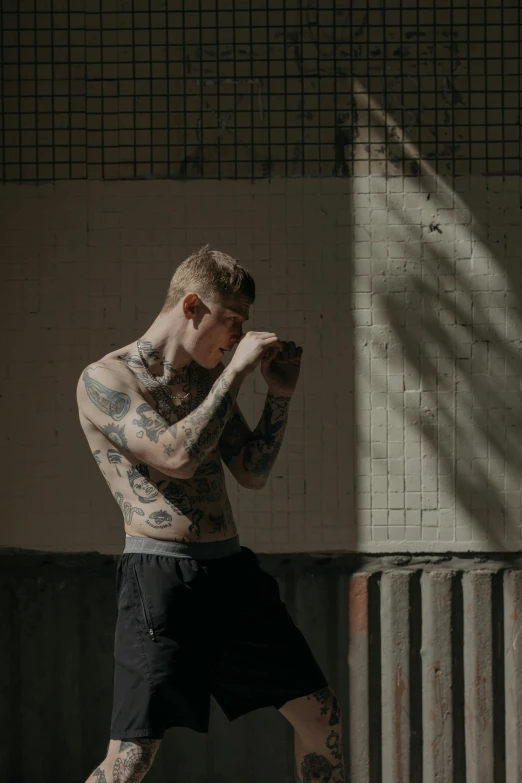 a man with tattoos is posing for a picture, inspired by Seb McKinnon, trending on pexels, in fighter poses, boyish, great light, lena oxton