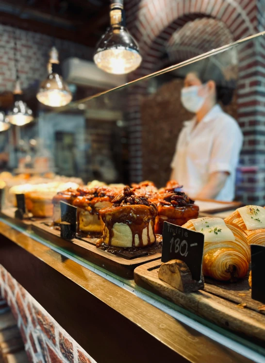 a row of pastries sitting on top of a counter, by Niko Henrichon, pexels, a person standing in front of a, daily specials, thumbnail, sakimichan