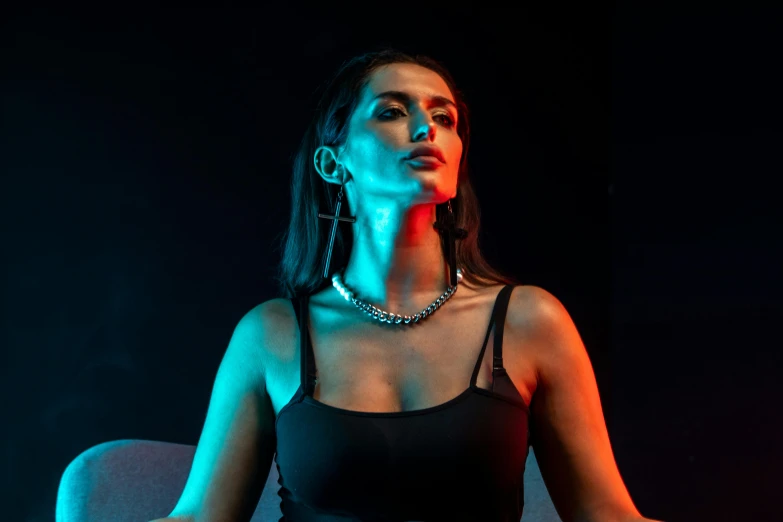 a woman in a black dress sitting in a chair, an album cover, inspired by Elsa Bleda, trending on pexels, holography, choker necklace, rapper bling jewelry, contour light effect!! 8 k, cyber necklace