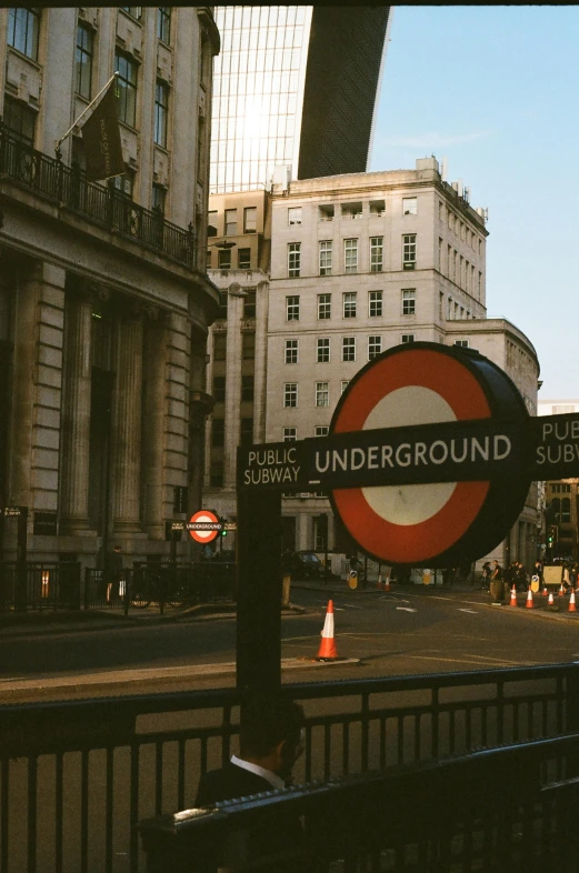 a red and white sign sitting on the side of a road, unsplash, underground comix, round buildings in background, trains, 🚿🗝📝, square