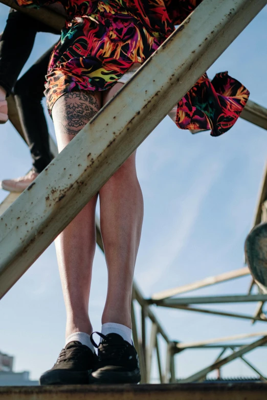 a man riding a skateboard up the side of a metal structure, by Jan Tengnagel, unsplash, renaissance, wearing skirt and high socks, multi - coloured, wearing shorts, view from bottom to top