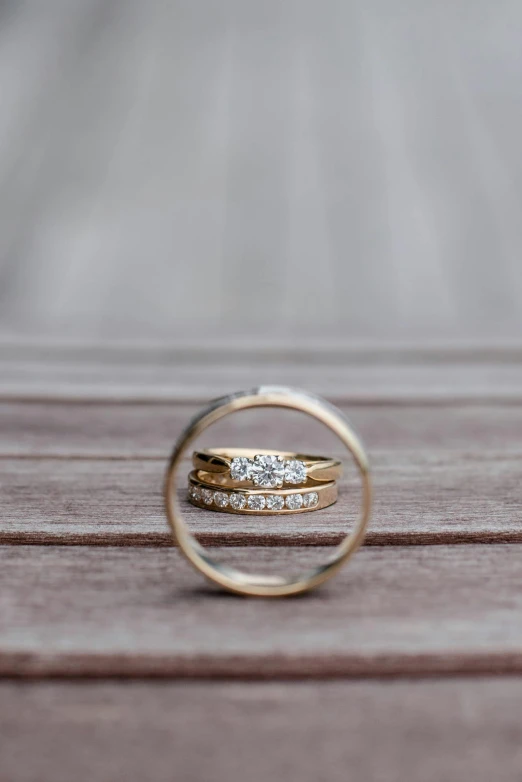 a couple of wedding rings sitting on top of a wooden table, a picture, unsplash, multiple stories, laura watson, enhanced, shot on sony a 7