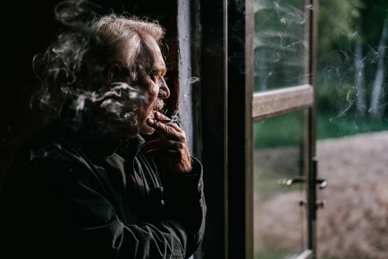 a close up of a person looking out a window, a portrait, by Jesper Knudsen, pexels contest winner, smoking with squat down pose, looking old, johnny cash, in a cabin