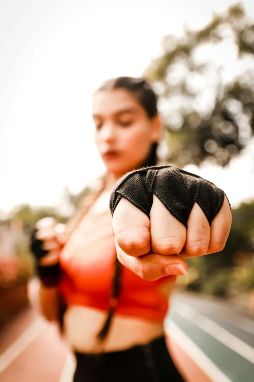 a woman in a sports bra top pointing at the camera, pexels contest winner, hand wraps, profile image, closeup of fist, beautiful surroundings