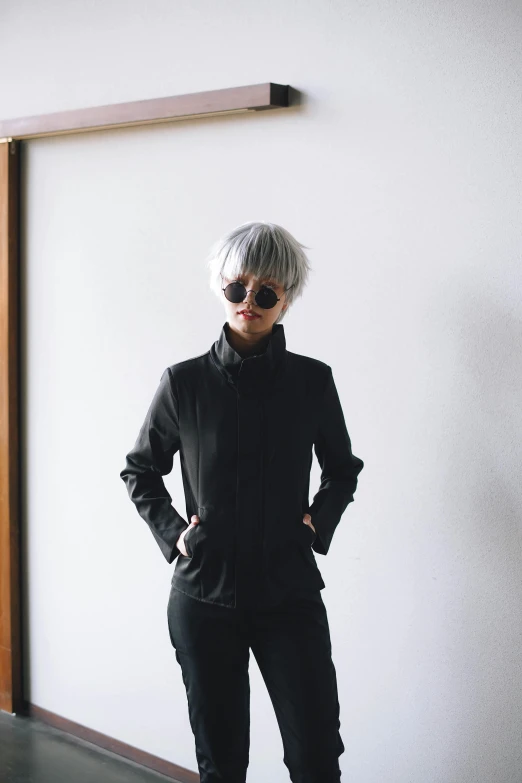 a woman standing in front of a white wall, inspired by Tadashi Nakayama, unsplash, short platinum hair tomboy, black turtle neck shirt, wearing track and field suit, with mirrorshades sunglasses