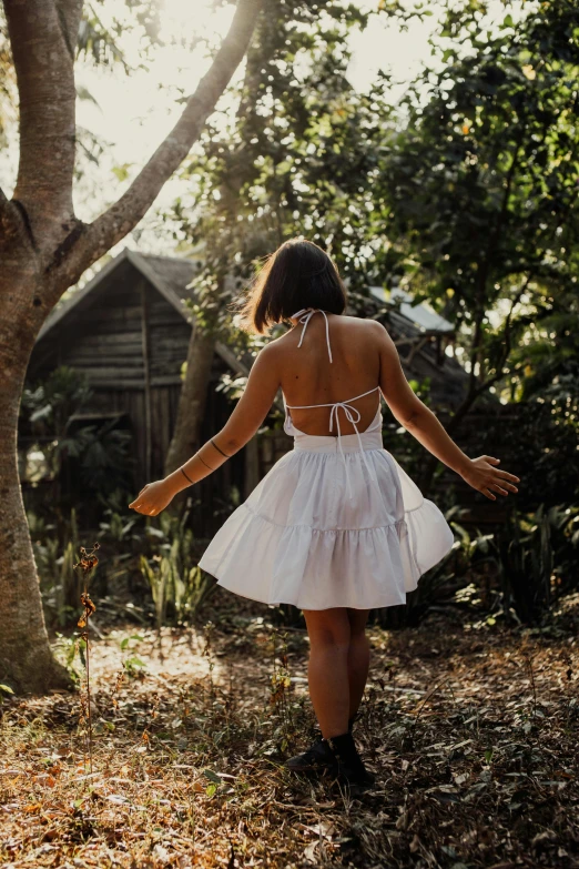 a woman in a white dress walking through the woods, pexels contest winner, white skirt and barechest, carefree, back view », in garden