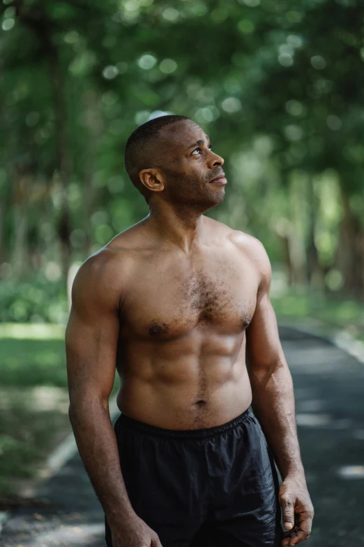 a shirtless man standing in the middle of a road, inspired by Terrell James, wearing fitness gear, man in his 40s, in front of a forest background, atiba jefferson