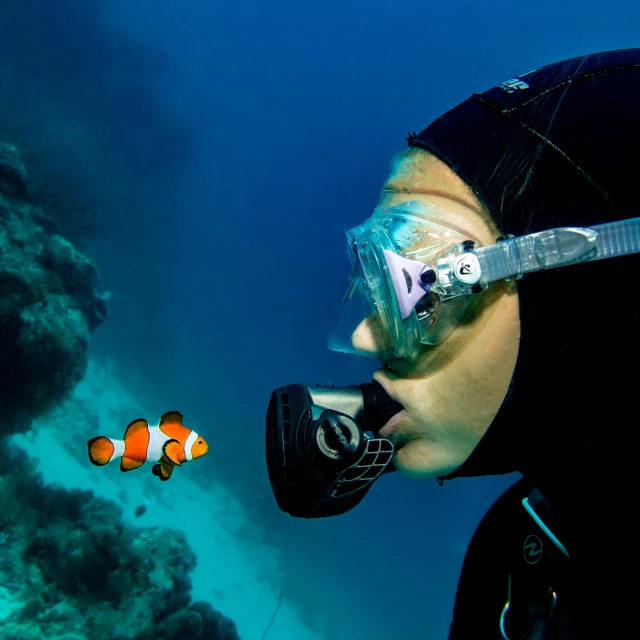 a man in a wetsuit and goggles looking at a clown fish, a portrait, by Emanuel Witz, pexels contest winner, islamic, a woman floats in midair, slide show, profile shot