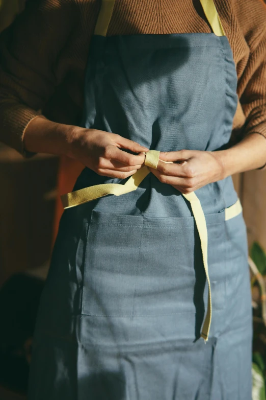 a close up of a person wearing an apron, by Jessie Algie, yellow and blue ribbons, sustainable materials, premium quality, dwell