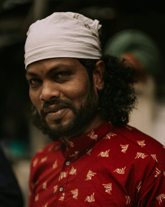 a man in a red shirt and a white hat, a character portrait, inspired by Ras Akyem, pexels contest winner, hurufiyya, bangladesh, looking smug, lgbtq, wearing traditional garb