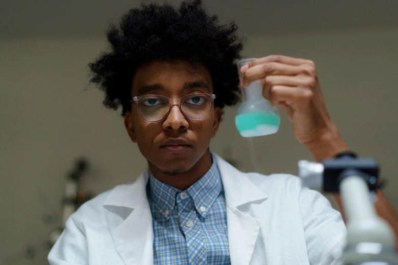 a woman in a lab coat holding a flask, by Washington Allston, pexels contest winner, east african man with curly hair, nerd, transparent goo, student