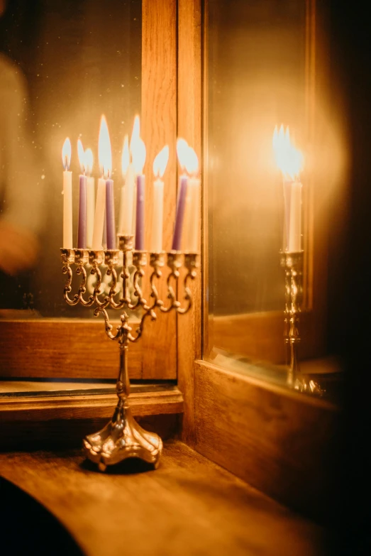 a group of lit candles sitting on top of a window sill, by Emanuel Witz, trending on unsplash, baroque, hebrew, glowing with silver light, chandelier, standing in a dimly lit room