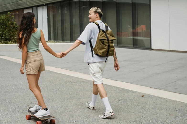 a couple of people riding skateboards down a street, trending on pexels, a backpack, man proposing his girlfriend, green and brown clothes, lgbtq