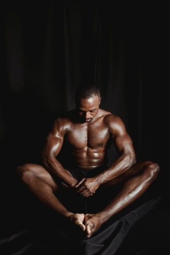 a man sitting on a bed with his legs crossed, inspired by Terrell James, pexels contest winner, mannerism, bodybuilder physique, black main color, sitting on the floor, textured skin