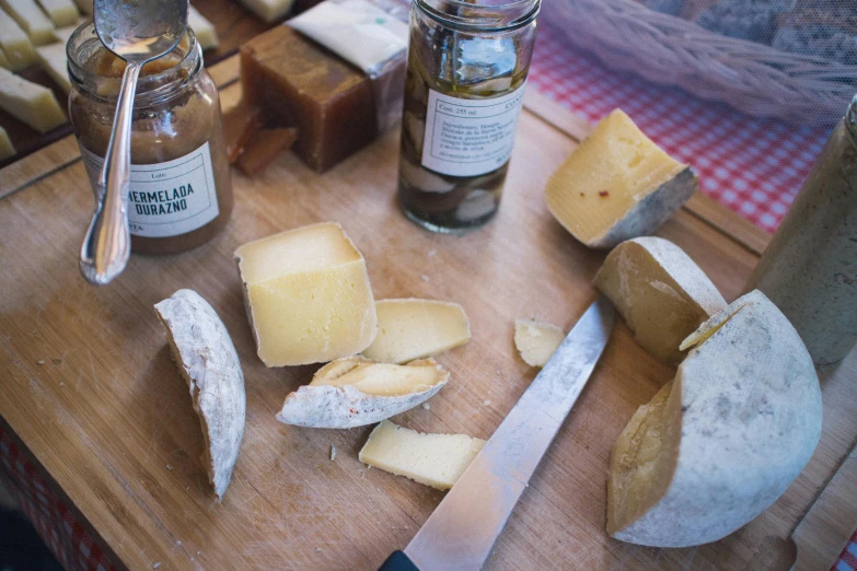 a wooden cutting board topped with different types of cheese, by Jessie Algie, lots of jars and boxes of herbs, thumbnail, chilean, uncropped