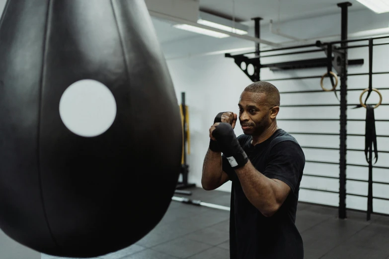 a man standing in front of a punching bag, by Sam Charles, pexels contest winner, background a gym, central hub, malcolm hart, working out