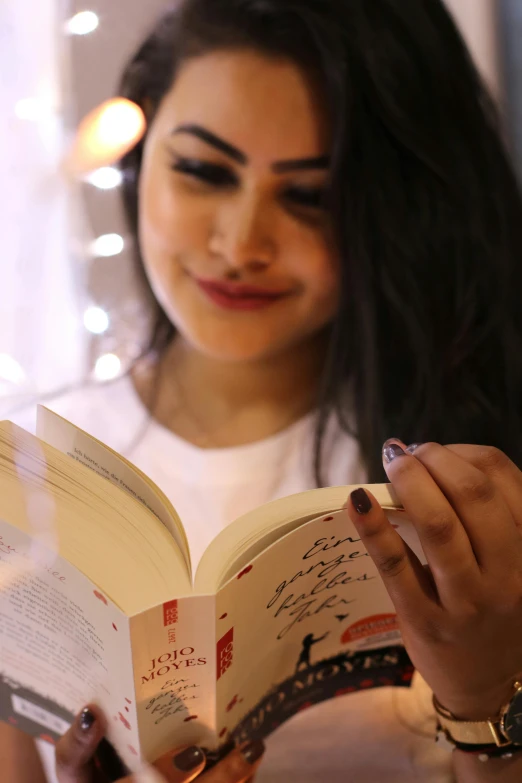 a woman sitting at a table reading a book, pexels contest winner, happening, young middle eastern woman, soft lights, profile image, gif