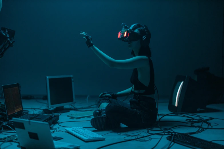 a man sitting on top of a floor next to a laptop computer, inspired by Simon Stålenhag, unsplash, video art, volumetric underwater lighting, photograph of a techwear woman, using a vr headset, coherent hands