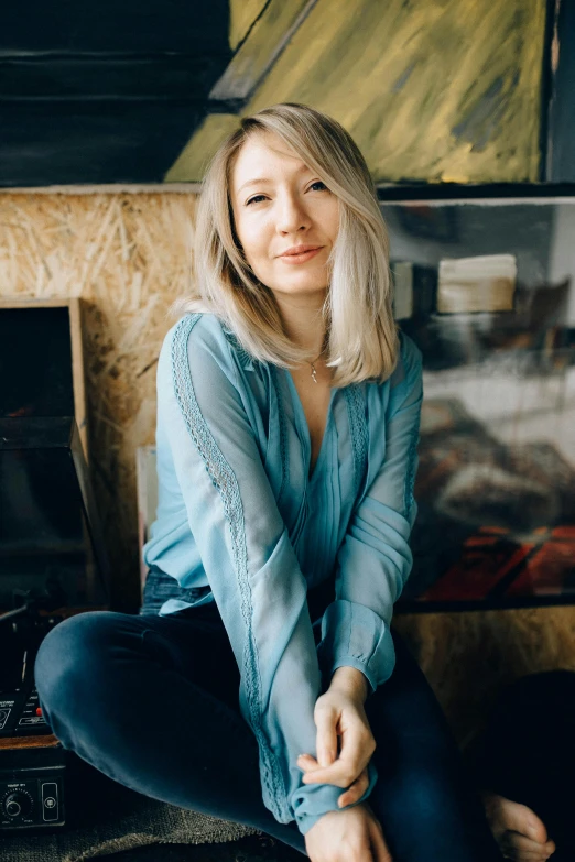 a woman sitting on the floor in front of a fireplace, a portrait, by Julia Pishtar, trending on unsplash, close up of a blonde woman, sitting on a stool, with hands in pockets, avatar image