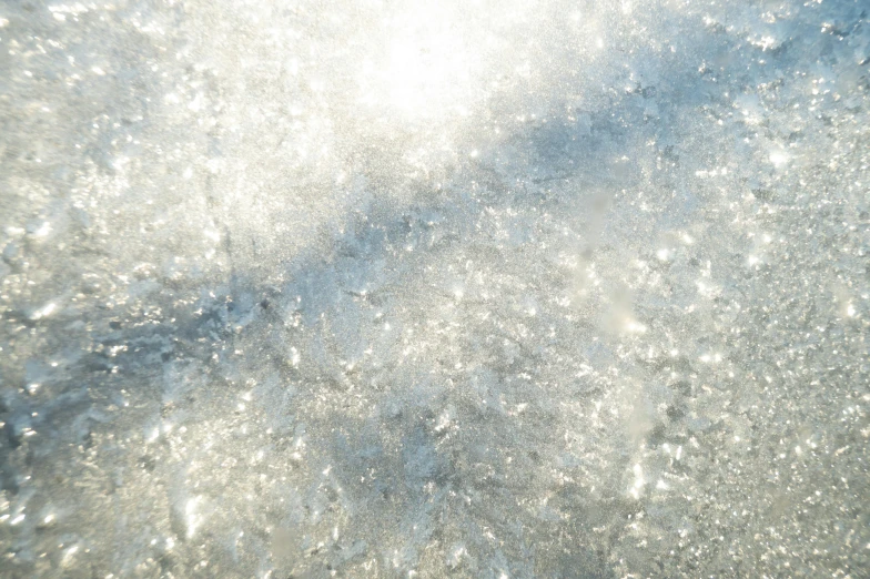 a man riding a wave on top of a surfboard, an album cover, inspired by Arthur Burdett Frost, trending on unsplash, light and space, close up of single sugar crystal, shiny silver, detailed texture, ground covered with snow