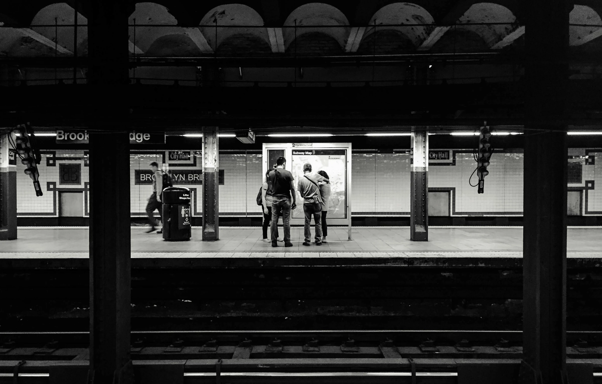 a black and white photo of people waiting at a train station, by Daniel Seghers, unsplash contest winner, mta subway entrance, ( low key light ), two men, with back to the camera