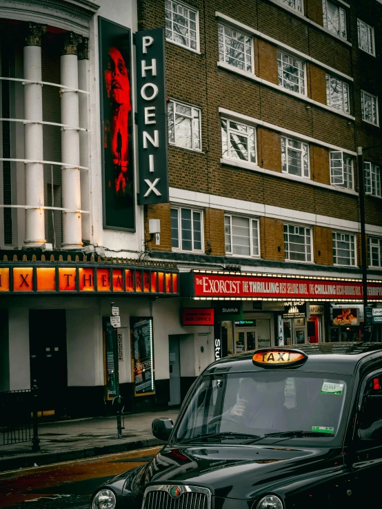 a taxi driving down a street next to a tall building, by Adam Rex, pexels contest winner, art nouveau, photo of the cinema screen, marquee, the phoenix, london