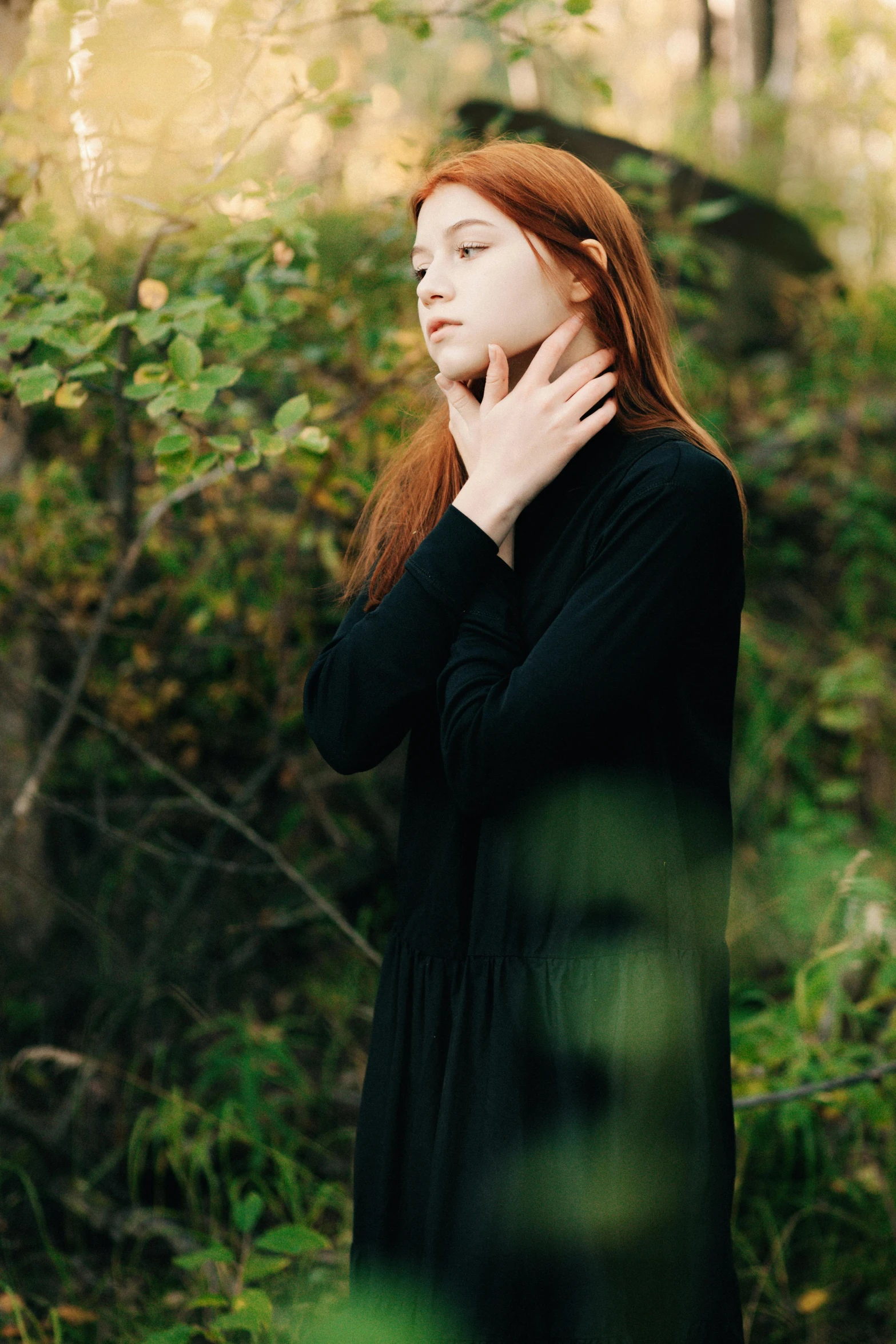 a woman in a black dress standing in a forest, inspired by Elsa Bleda, unsplash, renaissance, ( redhead, wearing turtleneck, greenery, natural soft pale skin