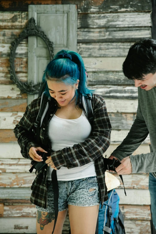 a man and a woman standing next to each other, inspired by Elsa Bleda, trending on pexels, visual art, messy blue hair, holster, in a cabin, teenager