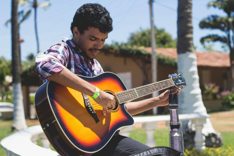 a man sitting on a bench playing a guitar, an album cover, by Alejandro Obregón, pexels contest winner, sunny day time, live performance, avatar image