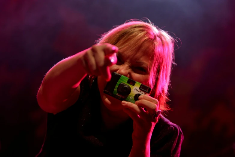 a woman taking a picture with a camera, psychic tv concert, shot with sony alpha 1 camera, bottom angle, toy camera