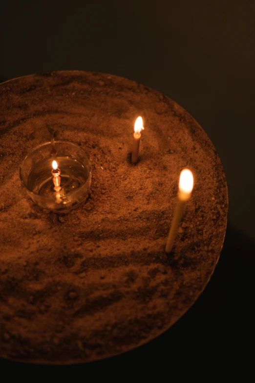 a group of lit candles sitting on top of a table, floating spiral sand, laura watson, seen from above, dusty lighting