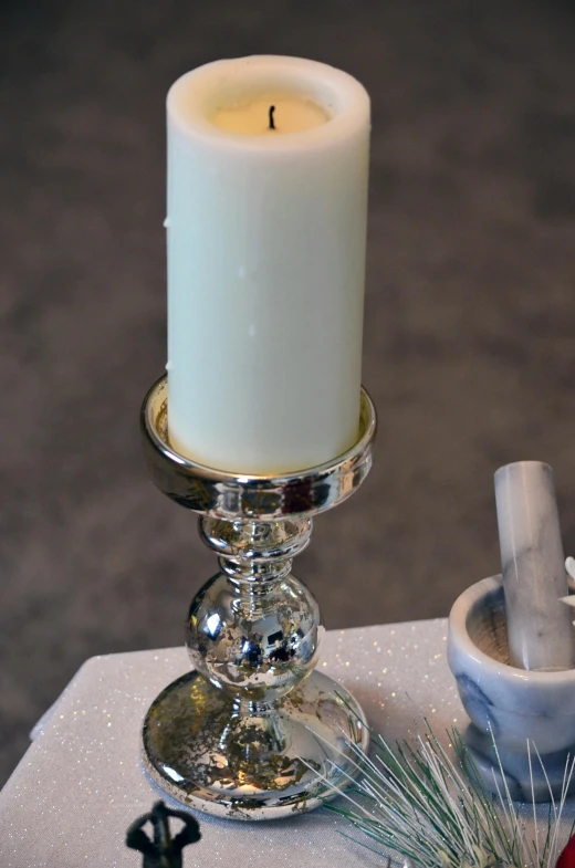 a candle that is sitting on a table, white and silver, marbled columns, glassware, pearl silverplate