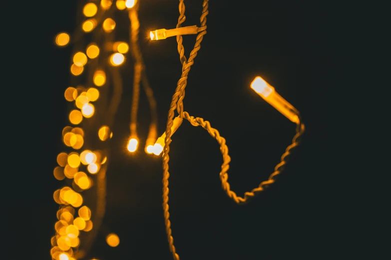 a string of lights hanging from the side of a building, trending on pexels, gold, on a dark background, yellow, festive