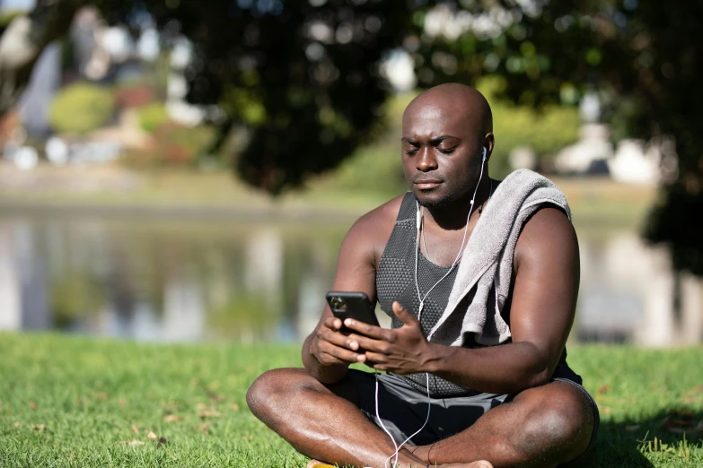 a man sitting on the grass looking at his cell phone, pexels contest winner, muscular bald man, aboriginal capirote, avatar image, programming