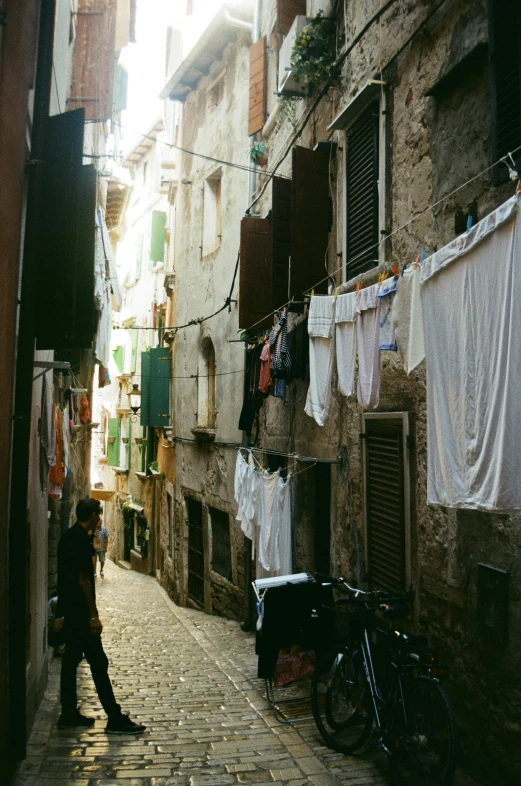 a narrow alley with clothes hanging out to dry, inspired by Jacopo Bassano, unsplash contest winner, renaissance, panoramic view of girl, photo taken on fujifilm superia, taken in the late 2000s, a handsome