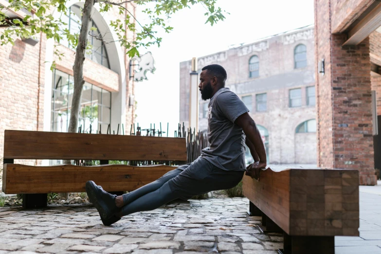 a man sitting on top of a wooden bench, working out, jaylen brown, grey pants and black dress shoes, thumbnail