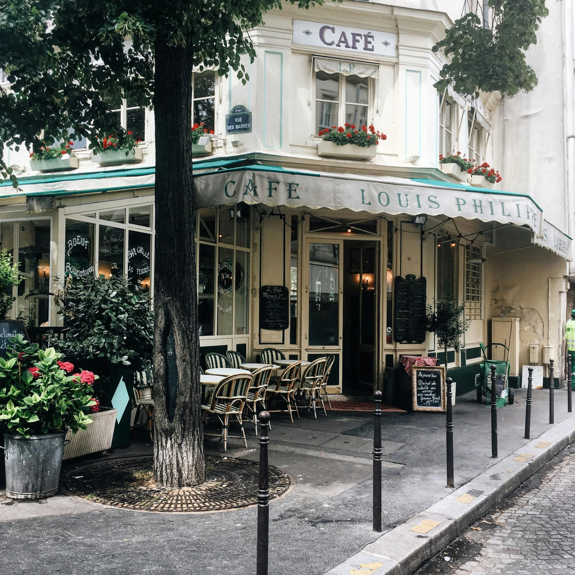 a cafe sitting on the side of a road next to a tree, a photo, unsplash, paris school, lush flora, square, 🚿🗝📝