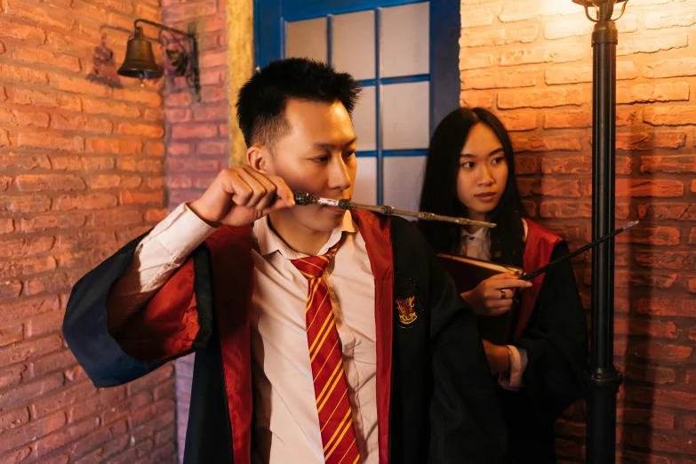 a couple of people standing next to a brick wall, pexels contest winner, hurufiyya, hogwarts gryffindor common room, chinese, wielding a magic staff, wearing robes and neckties