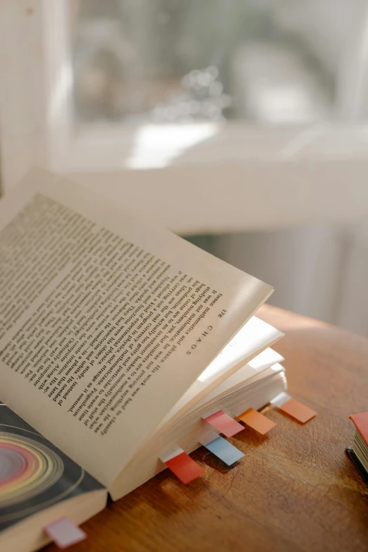 an open book sitting on top of a wooden table, pexels contest winner, light and space, studying in a brightly lit room, annotations, reading for a party, taken in the late 2010s