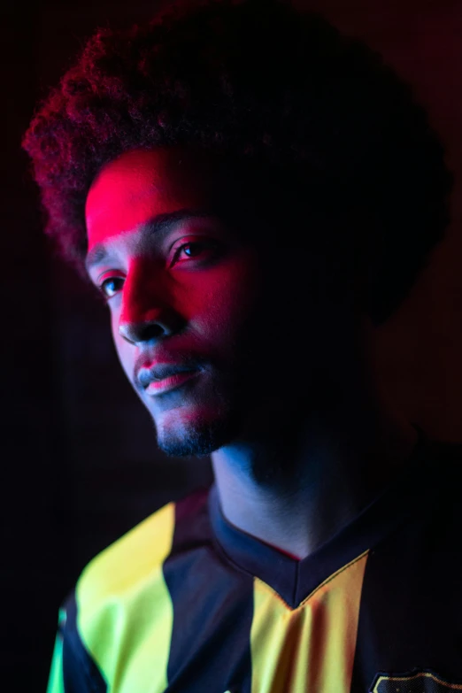 a man standing in front of a red light, a character portrait, inspired by Willian Murai, pexels, renaissance, black. yellow, soccer player, headshot profile picture, medium format. soft light