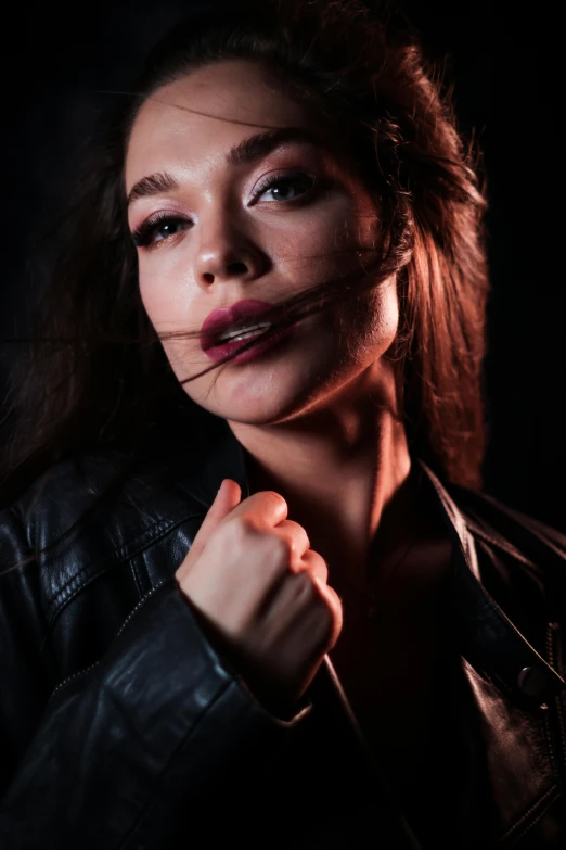 a woman in a leather jacket posing for the camera, a portrait, by Adam Marczyński, trending on pexels, photorealism, candid!! dark background, hailee steinfeld, parted lips, action glamour pose