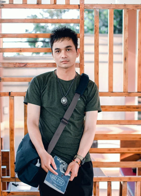 a man standing in front of a wooden structure, inspired by Rudy Siswanto, profile image, he is wearing a black t-shirt, фото девушка курит, a man wearing a backpack