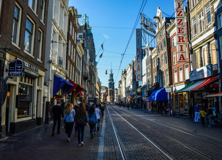 a group of people walking down a street next to tall buildings, a photo, by Jan Tengnagel, pexels contest winner, de stijl, delft, wires hanging above street, a quaint, brown