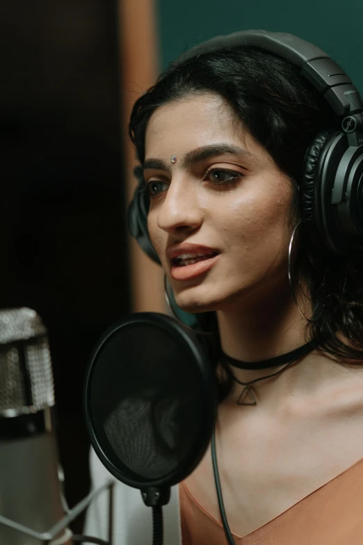 a woman wearing headphones in front of a microphone, trending on pexels, hyperrealism, bollywood, b - roll, lorde, studio quality