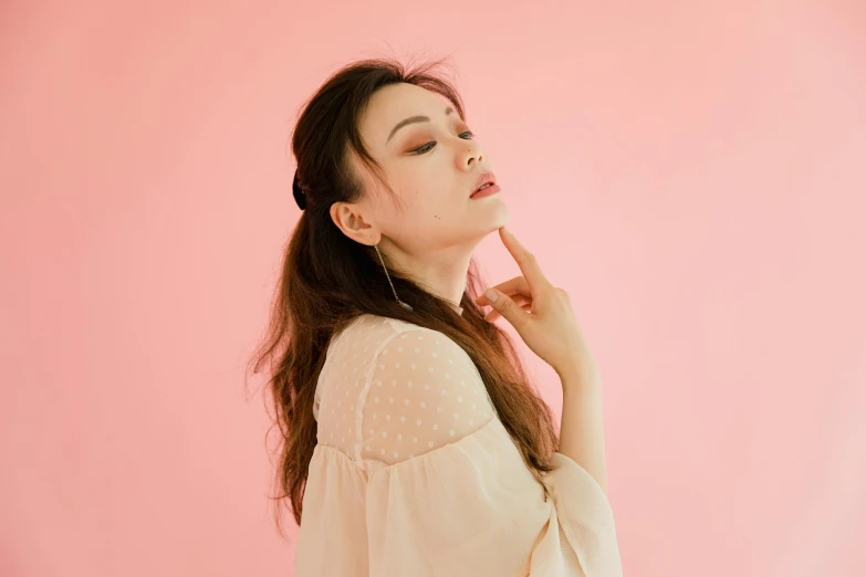 a woman standing in front of a pink wall, by Ayami Kojima, trending on pexels, elegant lady with alabaster skin, song nan li, plain background, looking her shoulder