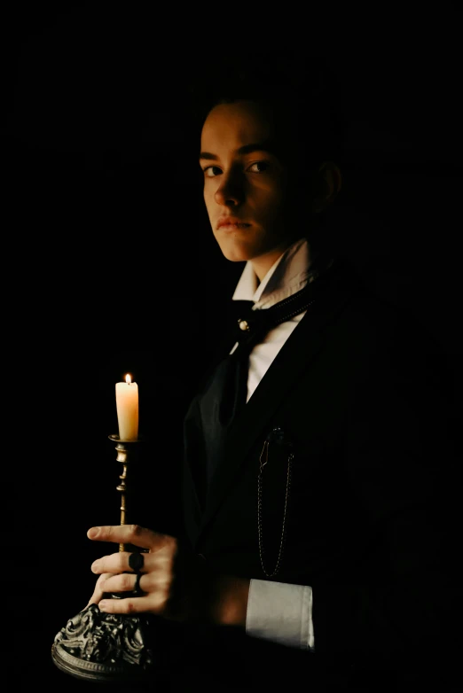 a man holding a lit candle in a dark room, an album cover, inspired by Ivan Kramskoi, romanticism, black tie, androgynous vampire, dark. no text, staff