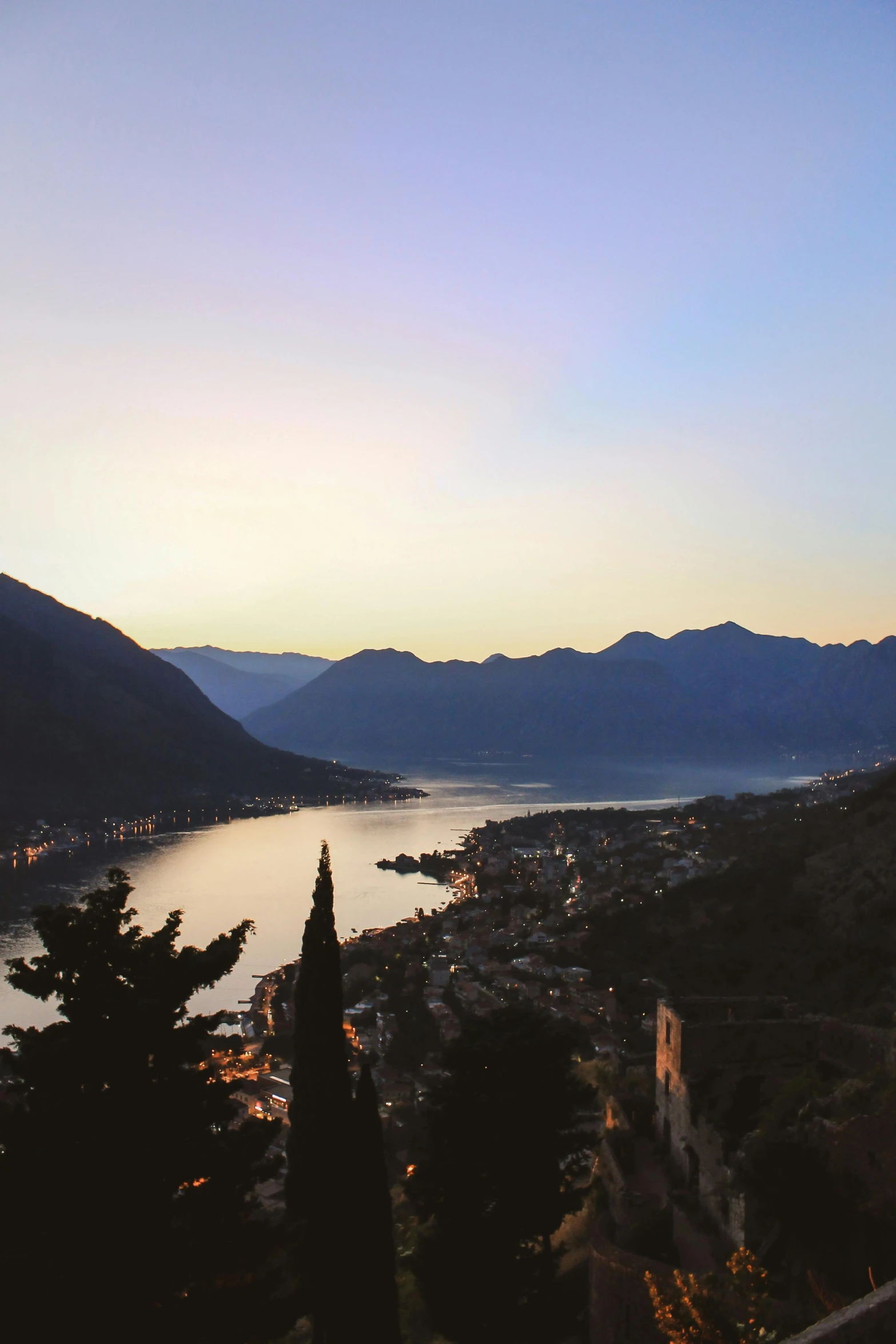 a large body of water sitting on top of a lush green hillside, pexels contest winner, romanticism, vista of a city at sunset, lakeside mountains, boka, winter sun